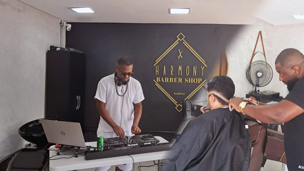 Dj tocando com seus equipamentos enquanto cabeleiro corta o cabelo do cliente